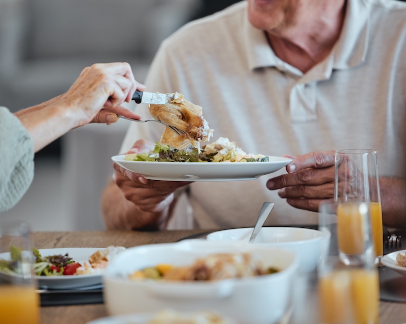 Senior man being served a plated meal at a dining table