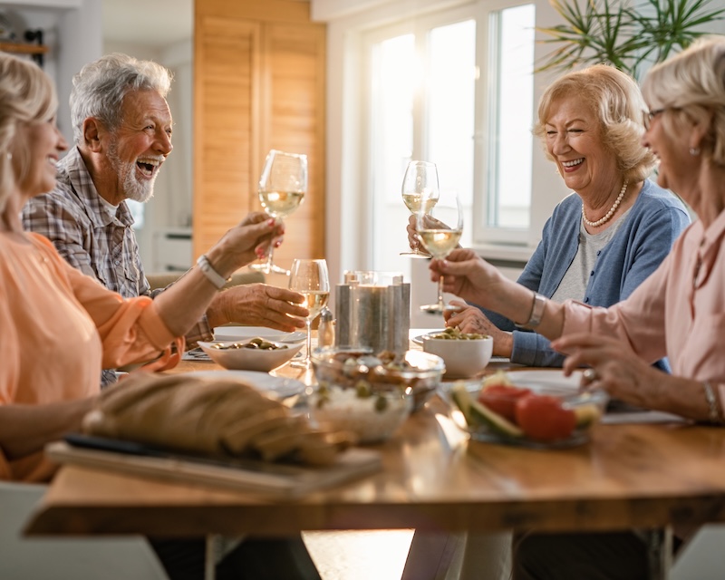 Smiling senior friends toasting with wine over a meal