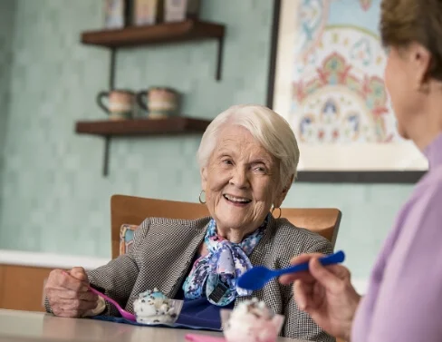 Smiling senior woman enjoying ice cream with a friend