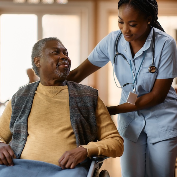 Nurse assisting a smiling senior man in a wheelchair