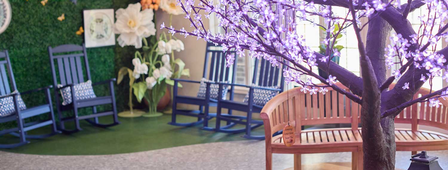 Garden-themed lounge with blue rocking chairs and blossom tree at Lorien Harmony Park