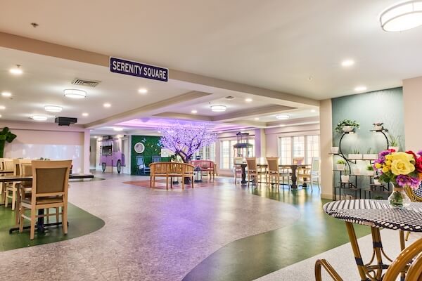 Serenity Square common area with seating and purple-lit trees at Lorien Harmony Park