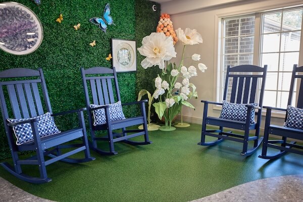 Garden-themed room with blue rocking chairs and flower wall at Lorien Harmony Park