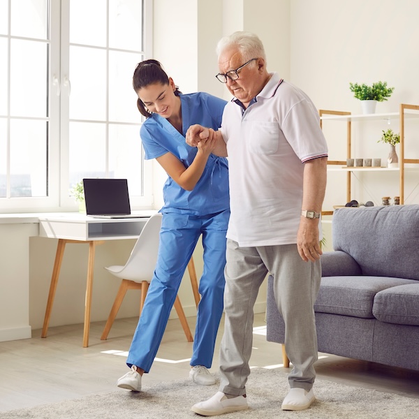 Caregiver helping a senior man walk at home