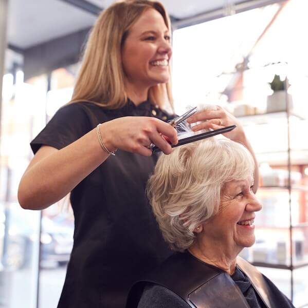 Stylist cutting a smiling senior woman's hair