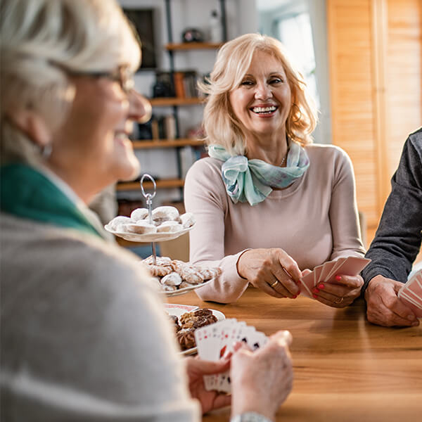 Smiling senior women playing cards together at a table
