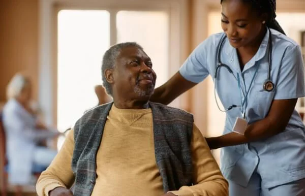 Nurse assisting a smiling senior man in a wheelchair